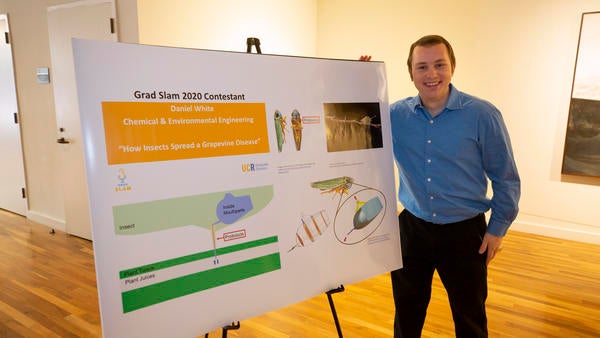Daniel White stands next to the poster of his slides