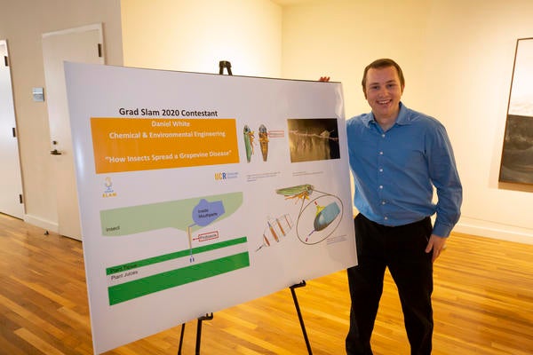 Daniel White stands next to the poster of his slides