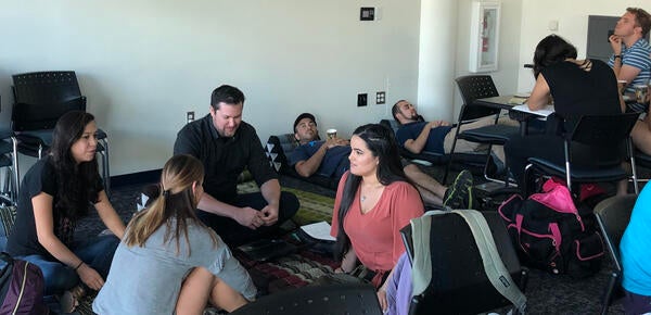 Grad students sit and lie on the floor relaxing