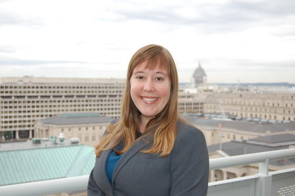 Emily Roberts smiling at the camera with a city view behind her. 