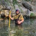 William from the waist up, standing in a river wearing waders, smiling straight ahead at the camera