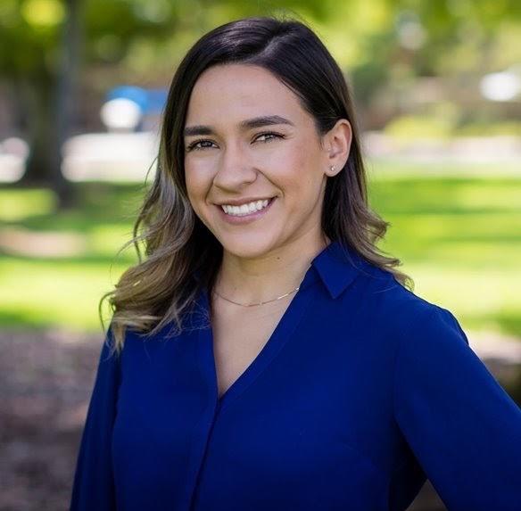 Nathaly smiling at camera from shoulders up, wearing bright blue shirt