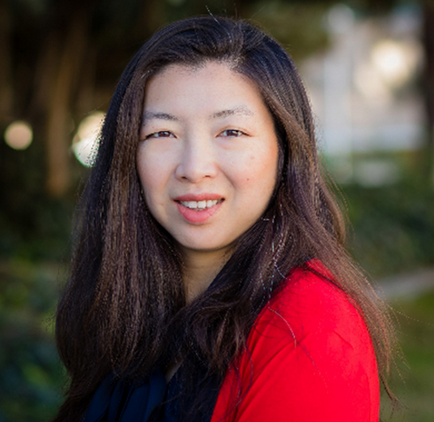 Vanessa Lee, dressed in red, looking over her left shoulder and smiling into camera