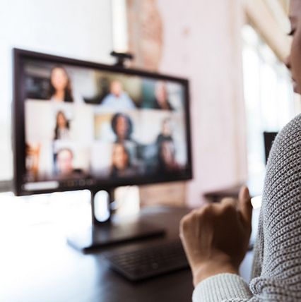 Phot of back of person, in focus, interacting with several others in Zoom, blurred