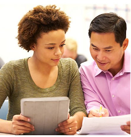 Two people sit next to each other and compare notes on different papers