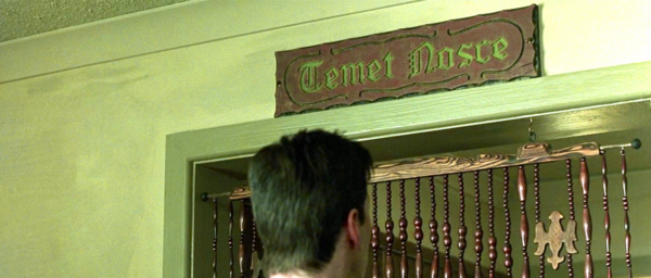 Neo (Keanu Reeves) in The Matrix stares up at a sign that says “Temet Nosce” in the Oracle’s apartment.