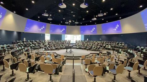 A circular seating lecture hall with a dais in the middle and projections all around the outer wall