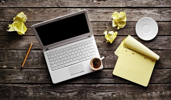 A desk with computer, paper, and coffee