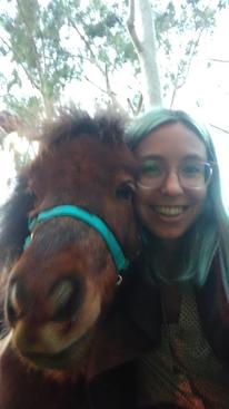 a selfie of a person smiling with their face right next to the face of a miniature pony